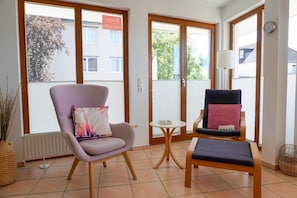 A room with a large window, a chair, a small table, and a bench. - (PAM4) Holiday apartment "Leffler" - Holiday apartment "Leffler" up to 2 persons (Timmendorfer Strand)