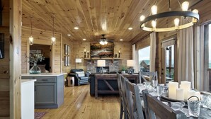 A wooden cabin interior with a dining area, kitchen, and living space. - Majestic 3BR Smoky Cabin + Views + Small Pet Friendly + Games + Near Dollywood (Pigeon Forge)