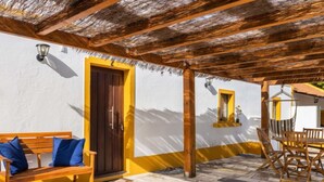 Un patio cubierto con un banco de madera, una mesa y sillas.
