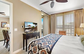 Une chambre d’hôtel avec un lit, un bureau avec une télévision, une chaise et une vue sur l’extérieur.