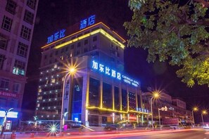 A multi-story hotel with illuminated signage, a prominent entrance, and a street view.