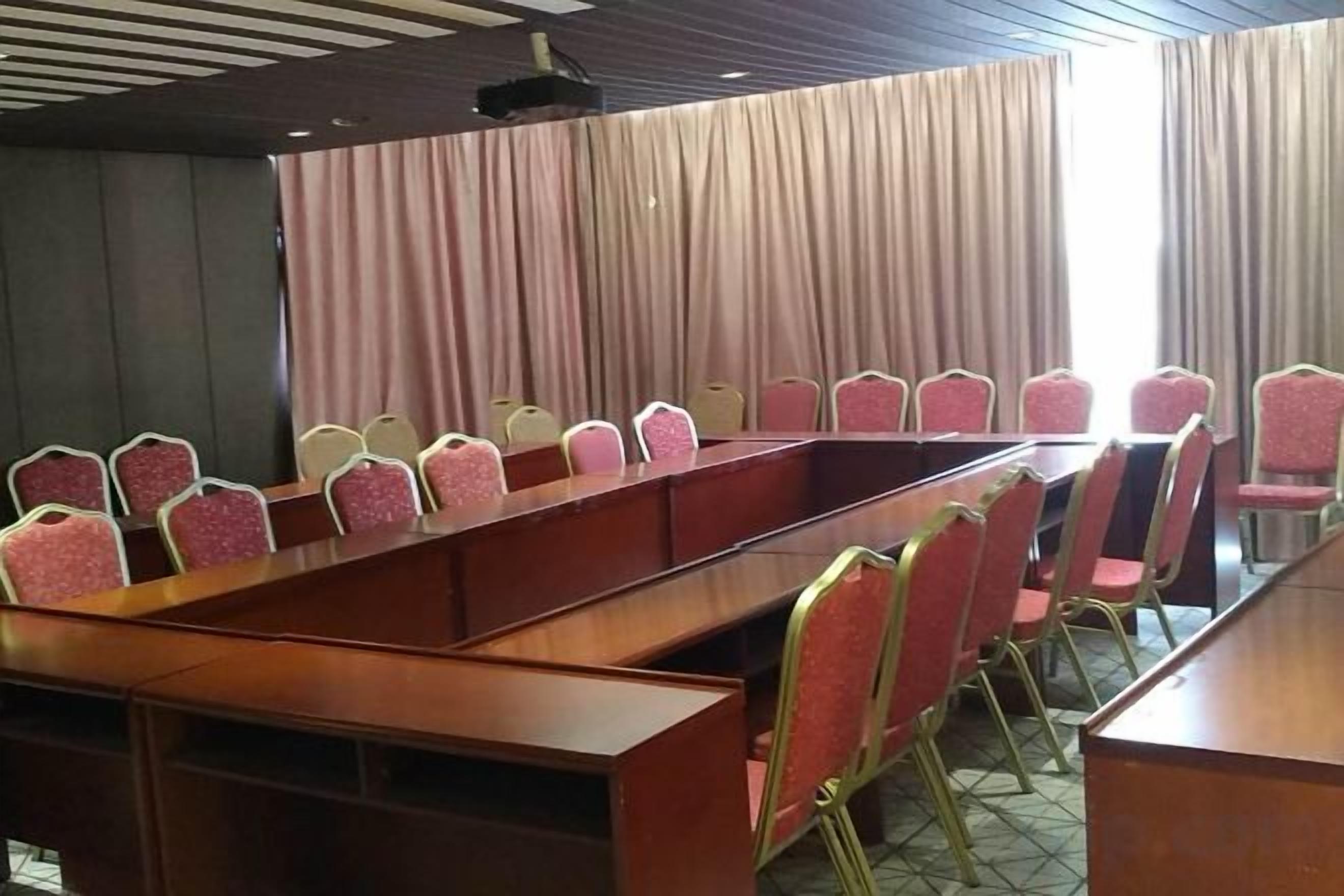 Una sala de conferencias con una larga mesa y filas de sillas.