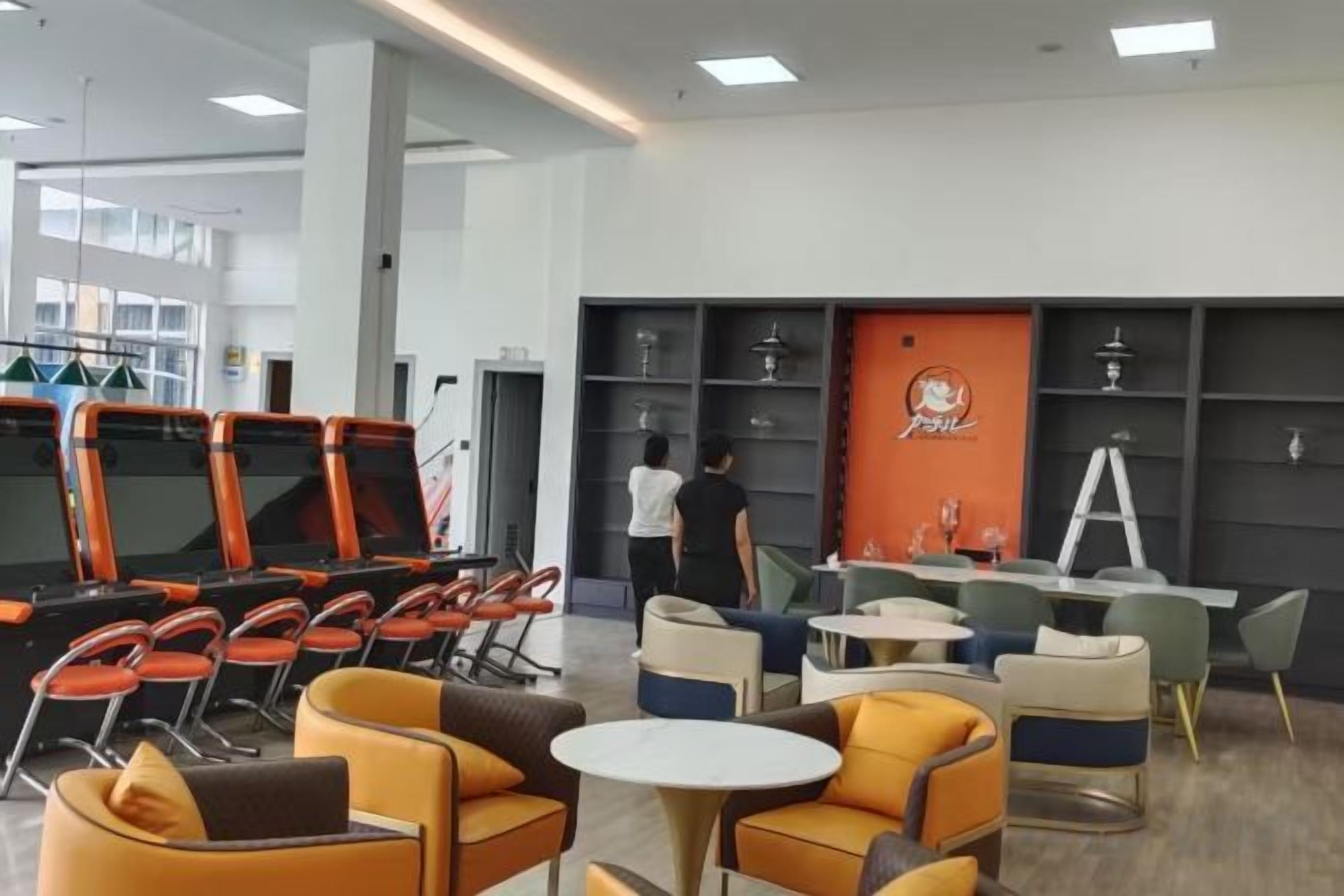Un espace lounge moderne, doté de différents types de sièges, d’un comptoir et d’un mur avec des étagères.