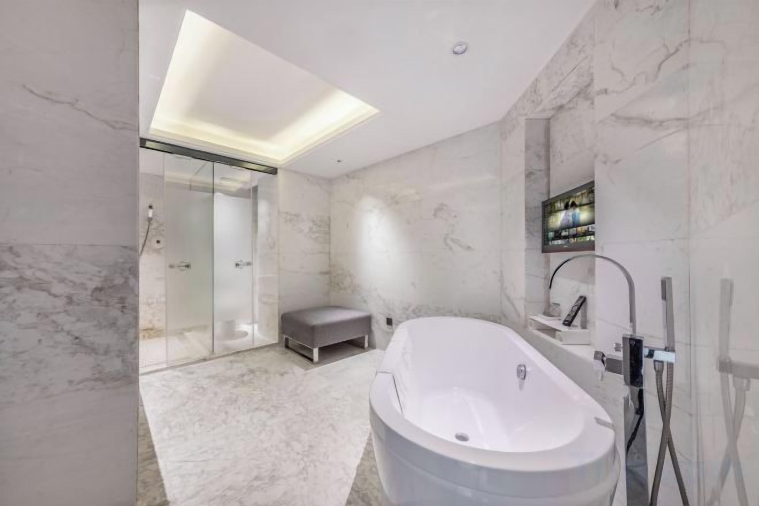A modern bathroom with a freestanding bathtub, a glass-enclosed shower, and a marble floor.