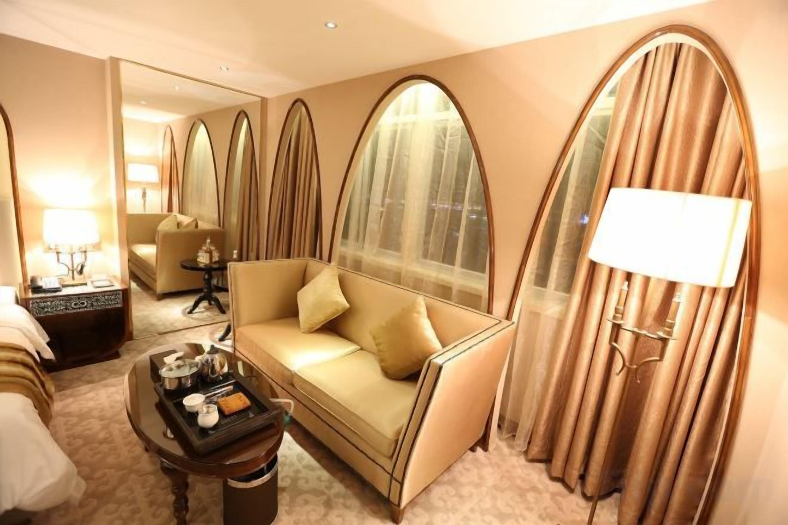 Une chambre d’hôtel avec un canapé, une table basse, une lampe et un miroir.