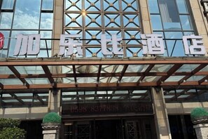 A hotel entrance with a modern glass facade and a sign indicating the name and contact information. - Sanming Caribbean Fortune Hotel (Sanming)