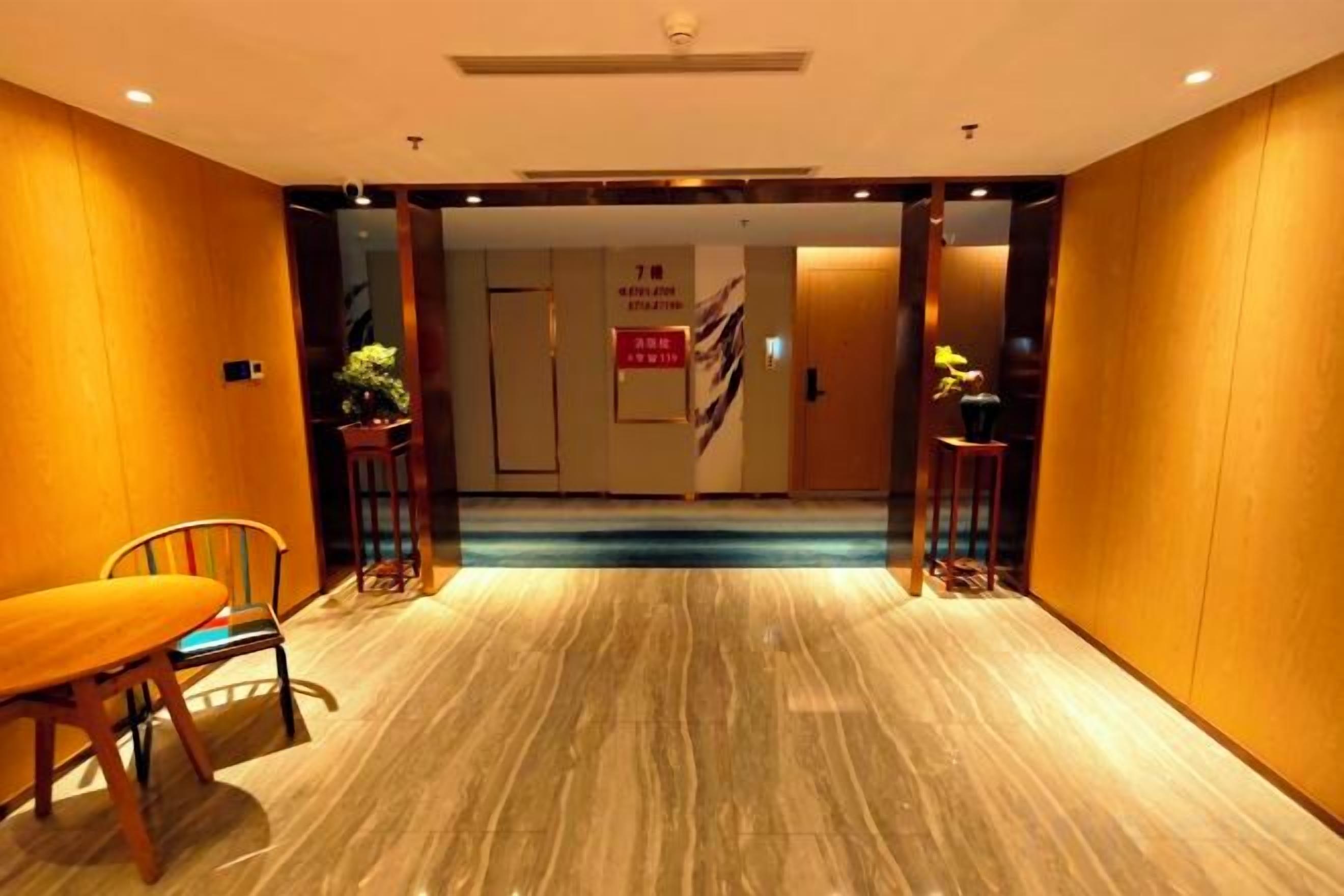 Vestíbulo de hotel con suelo de mármol, mostrador de recepción y escalera que conduce a las plantas superiores.