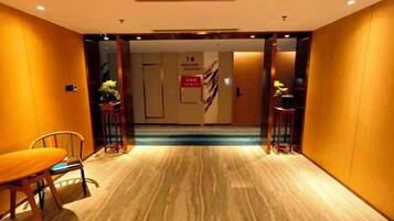 Vestíbulo de hotel con suelo de mármol, mostrador de recepción y escalera que conduce a las plantas superiores.