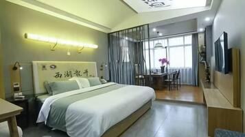 A modern hotel room with a large bed, a desk, and a dining area.