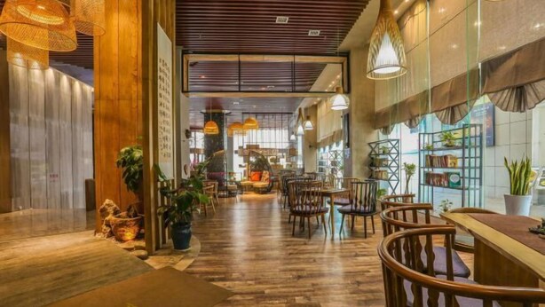 Un espacio interior amplio con suelo de madera, varias mesas y sillas, y lámparas colgantes.