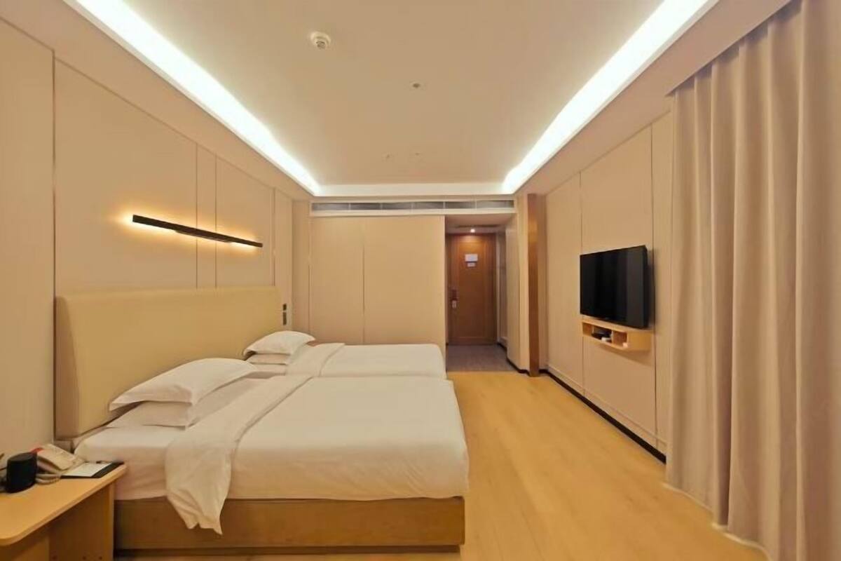 Habitación de hotel con cama doble, televisor de pantalla plana montado en la pared y mesita de noche con lámpara.