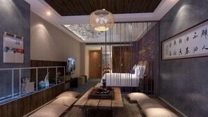 Una habitación de hotel moderna con techo de madera, una cama grande, una mesa de comedor con cojines y una lámpara colgante.