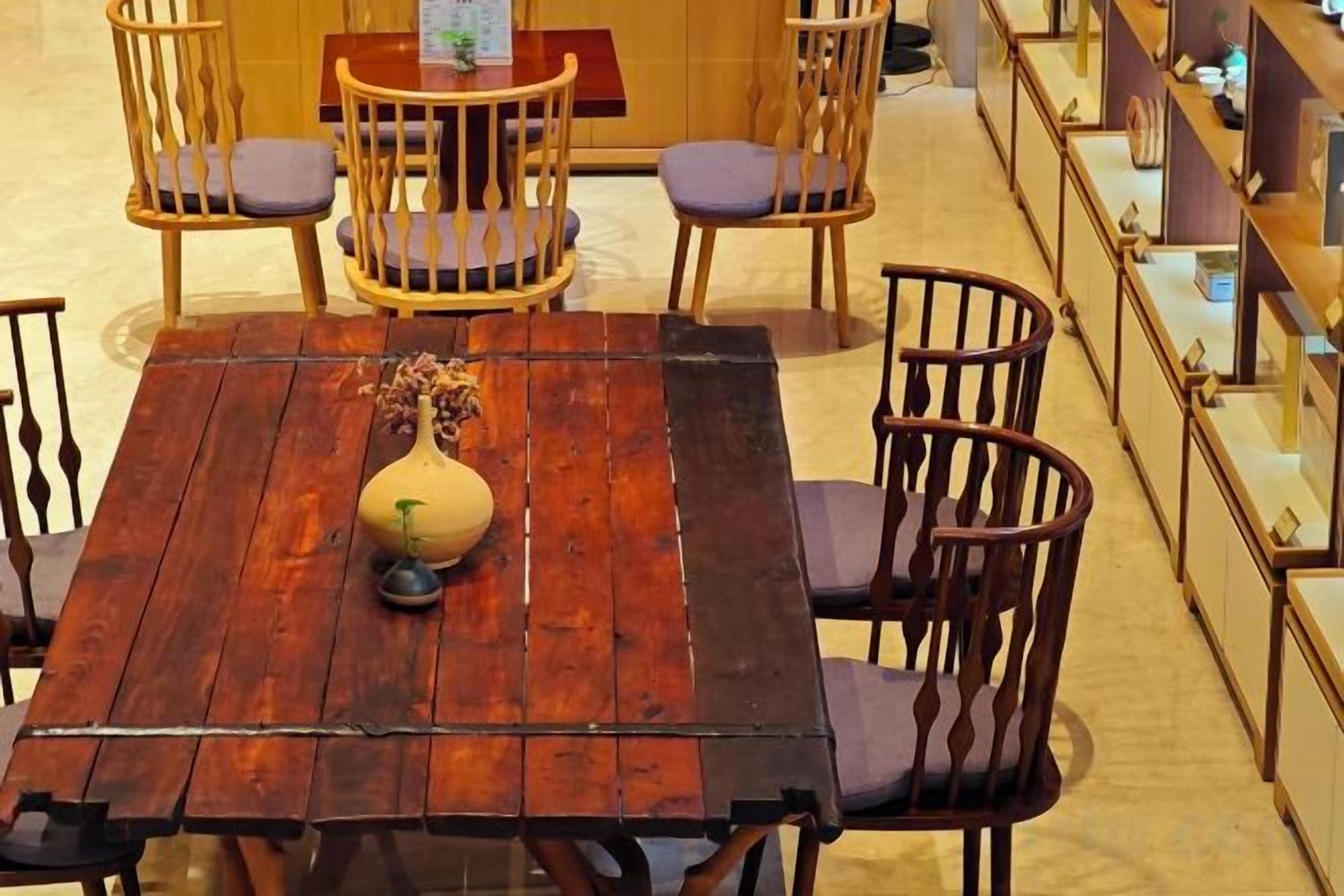 Una mesa de comedor de madera con un centro de mesa en una jarra, rodeada de sillas de madera con asientos acolchados.