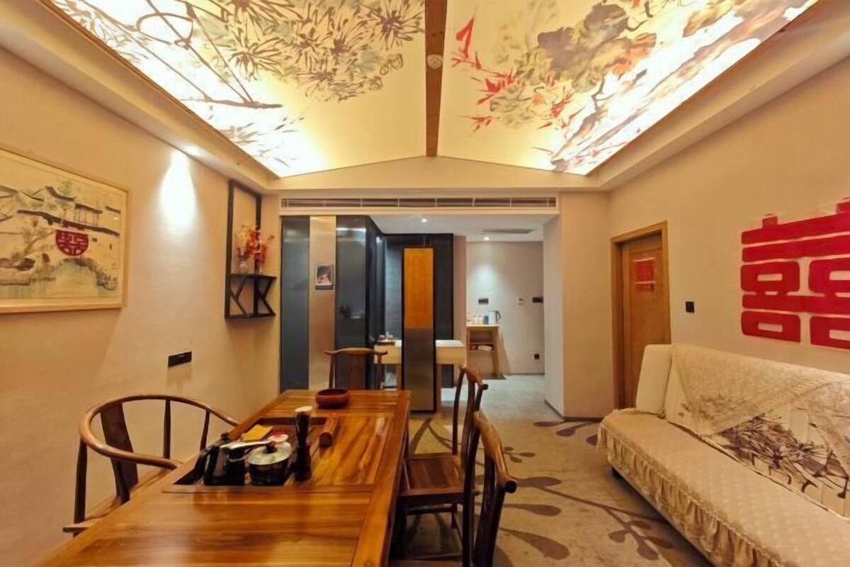 Un comedor con mesa y sillas de madera, un sofá y obras de arte en las paredes.
