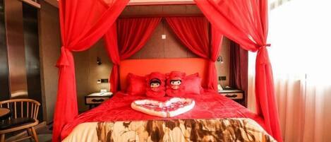 A bedroom with a canopy bed, a heart-shaped pillow, and two plush toys on the pillows.