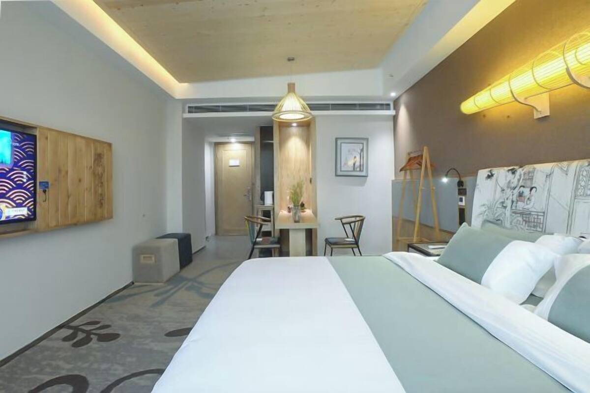 Una habitación de hotel con una cama, un escritorio, una silla, una lámpara y un televisor.