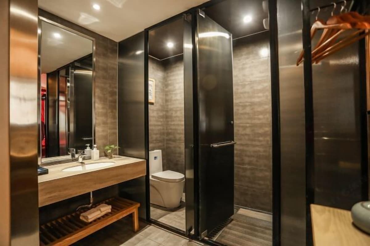 A modern bathroom with a wooden vanity, a large mirror, a toilet, and a shower enclosure.