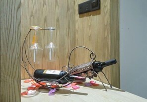 A wine bottle on a table with rose petals and a decorative stand. - Yemingju Hotel (Zhuzhou)
