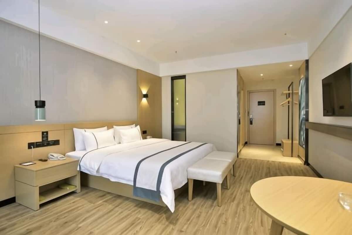 A hotel room with a bed, bedside table, bench, and a small table.