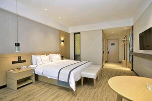 Una habitación de hotel con cama, mesita de noche, banco y una pequeña mesa.