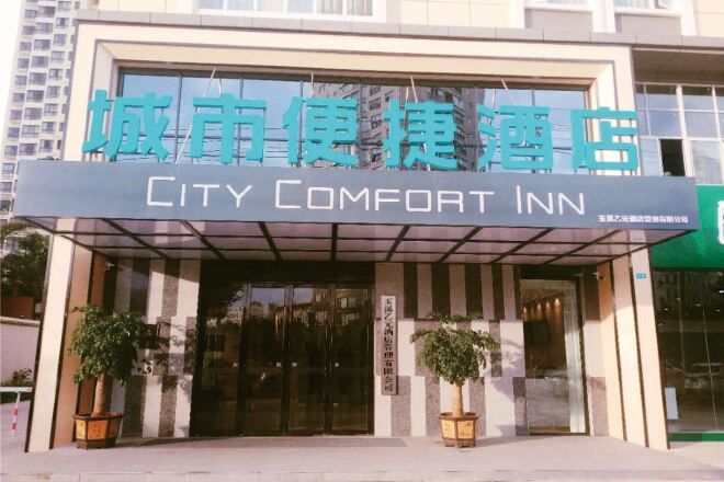 Entrada de un hotel con un letrero que dice 'City Comfort Inn' y un área de acceso cubierta.