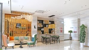 Un moderno hall de hotel con un sofá, sillas, una mesa y una estantería.