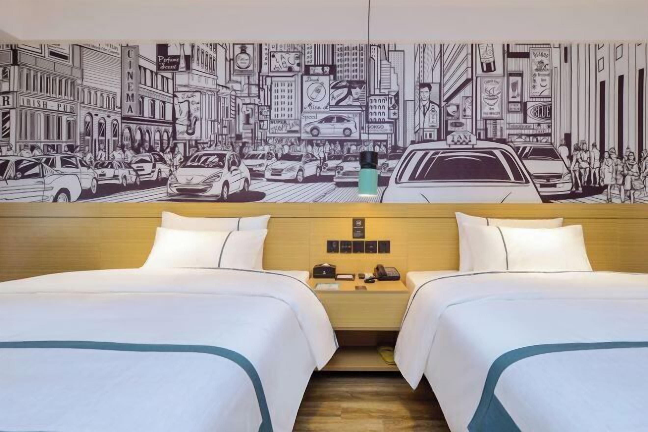 A hotel room with two beds, a wooden headboard, a nightstand with a phone, and a wall mural of a city street scene.