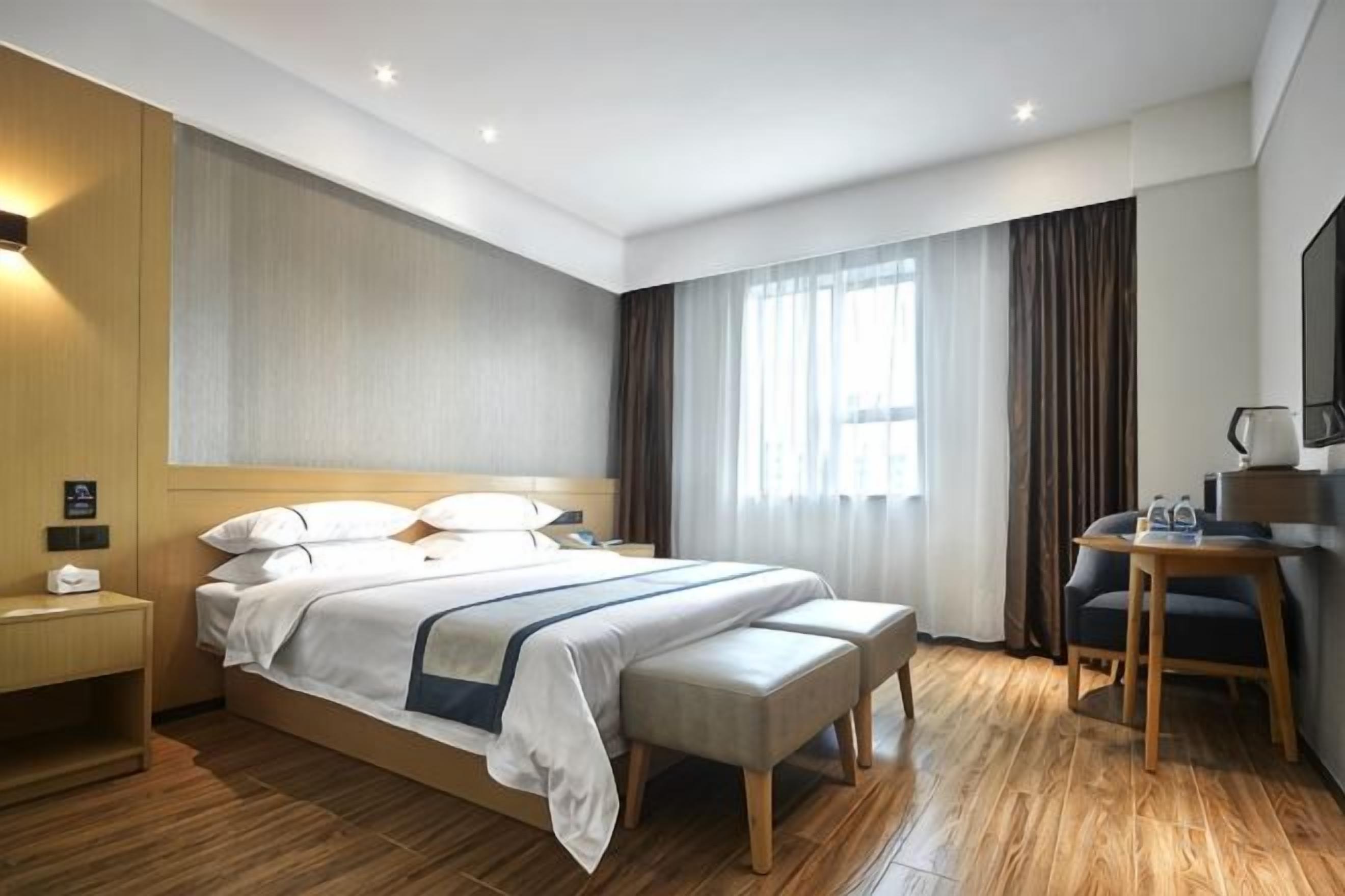 A hotel room with a large bed, a desk, and a chair.