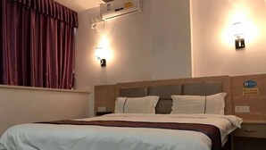 A hotel room with a bed, two wall-mounted lights, a window with curtains, and a wall-mounted air conditioner. - Yuekai Hostel (Dongguan)