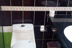 Ein Badezimmer mit Toilette, Waschbecken und Toilettenpapierhalter.