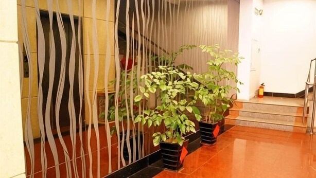 A reception area with a modern design, including a decorative wall, potted plants, and a staircase. - Yuekai Hostel (Dongguan)