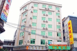 Un hotel de varios pisos con fachada plana, múltiples unidades de aire acondicionado y varias ventanas.