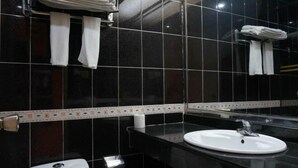 A bathroom with black tiled walls, a white sink, and two towel racks with folded towels. - Yuekai Hostel (Dongguan)