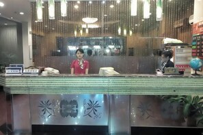 Un comptoir d’accueil avec une cloison en verre, un téléphone et un écran numérique.