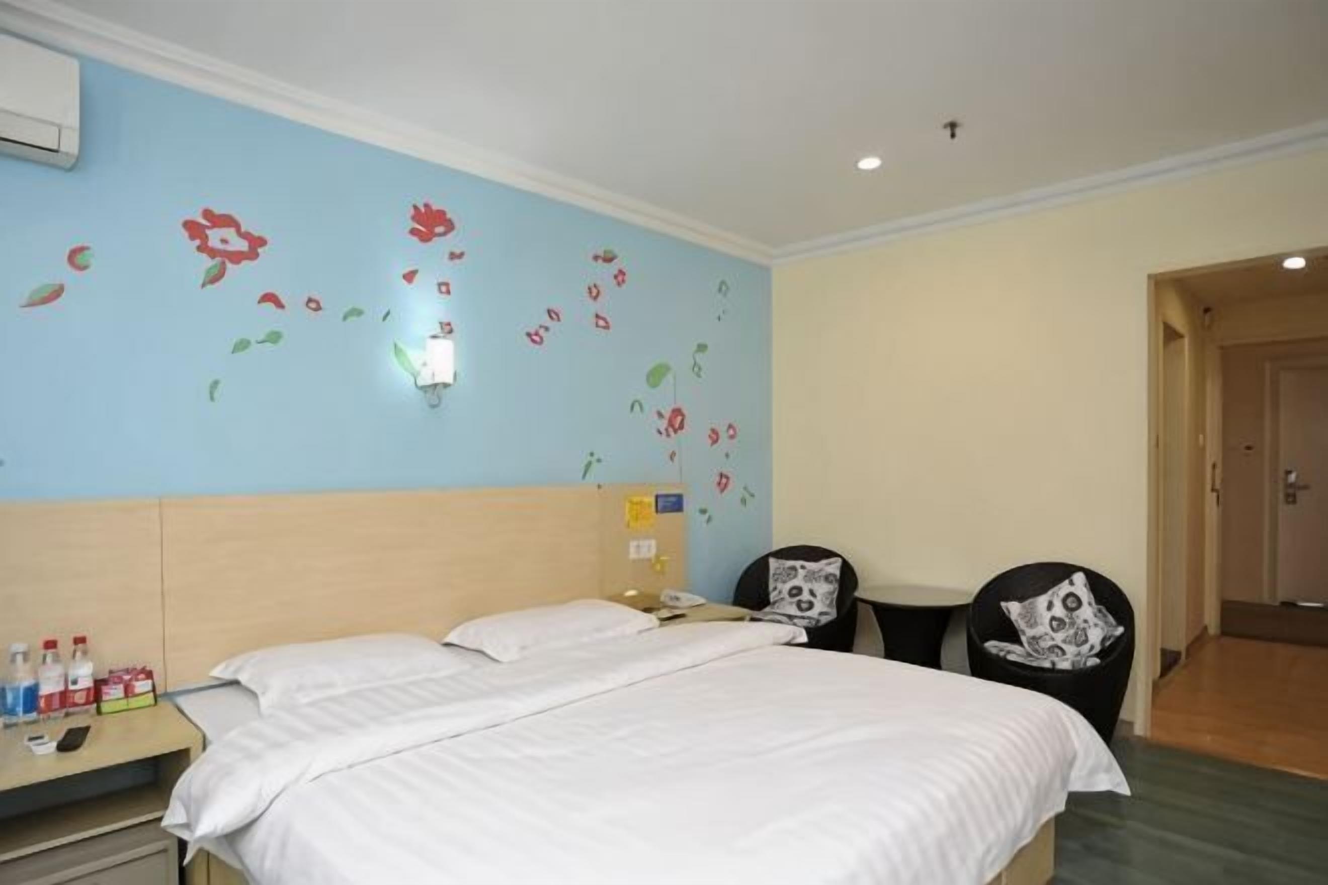 Una habitación de hotel con una cama, un escritorio con una silla, un teléfono en la pared y una puerta.