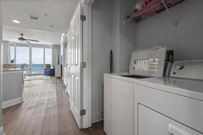 Laundry room with front-loading washer and dryer, ceiling fan, and natural light.