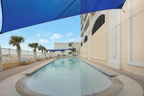 Relax by the serene pool surrounded by lounge chairs and a shaded canopy.