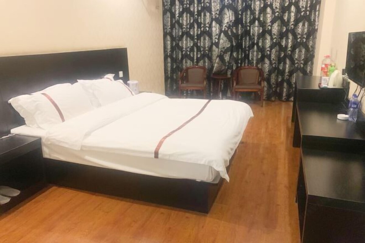 Una habitación de hotel con una cama, una mesita de noche, un televisor y una silla.