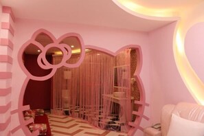Una habitación con una decoración en tonos rosados, que incluye una pared con un hueco en forma de corazón y una cortina colgante.
