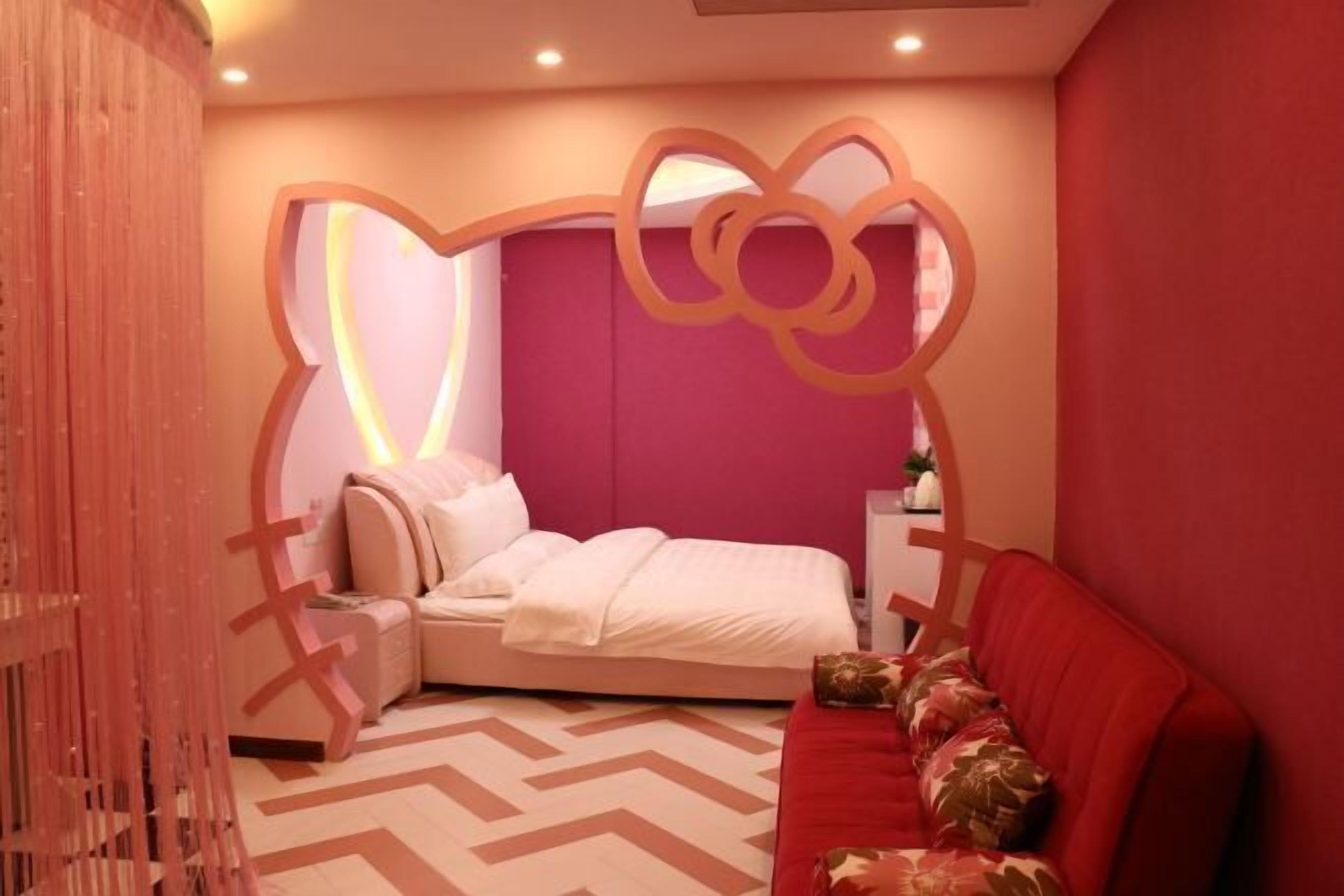 A bedroom with a bed, a red sofa, a decorative wall, and a patterned floor.