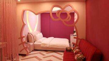 A bedroom with a bed, a red sofa, a decorative wall, and a patterned floor.