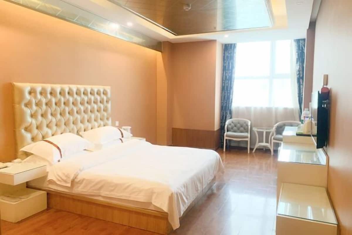 A hotel room with a large bed, bedside tables, a desk, and a chair.