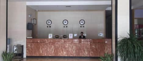 En reception med receptionist, et ur og en skilt med hotellets navn.