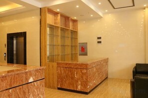A hotel reception area with a marble reception desk, a glass display cabinet, a black leather chair, and a door to the left. - City 118 Hotel Chain (Cangzhou Southern Hemisphere) (Bozhou)