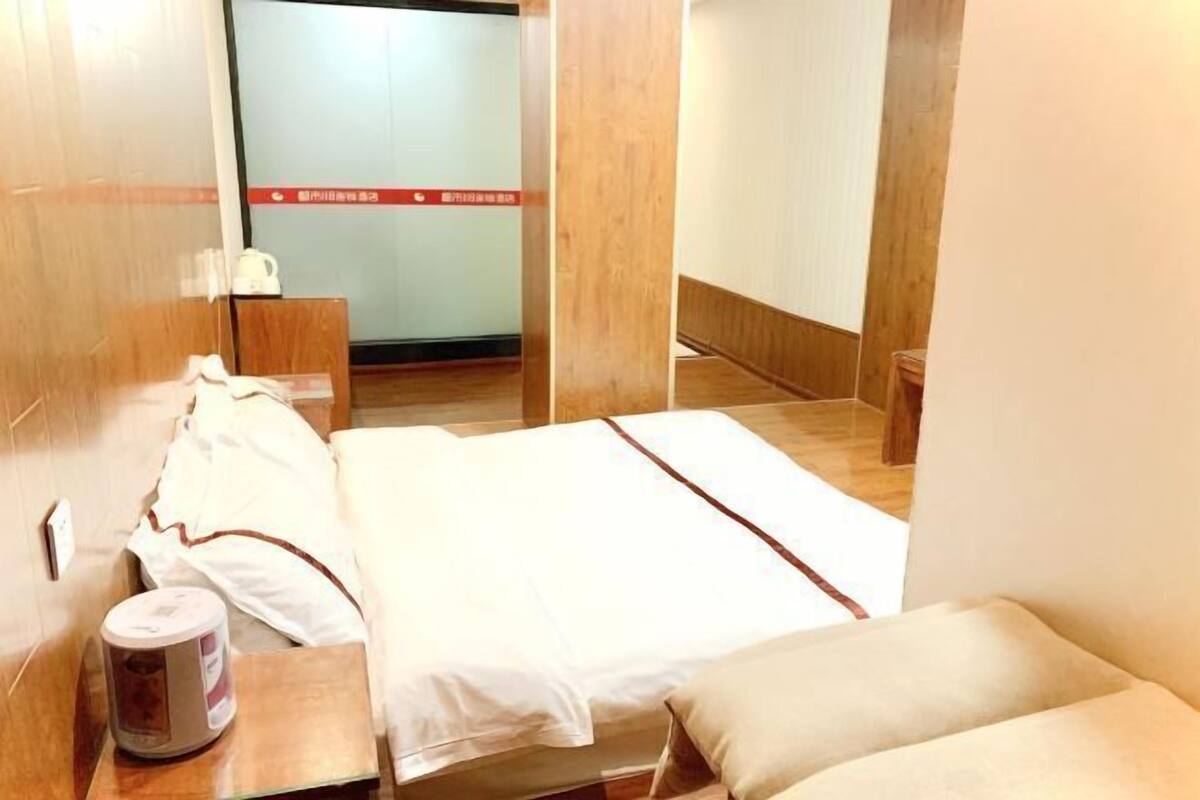 A hotel room with a bed, bedside table, and a small table with a tissue box.