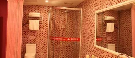 Une salle de bain avec un carrelage à motifs, une douche en verre, un lavabo blanc et un miroir.