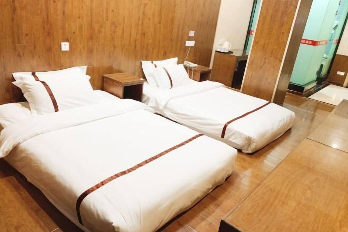 A hotel room with two beds, wooden paneling on the walls, and a tiled floor.