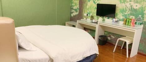 A bedroom with a bed, a desk, a television, and a small stool.