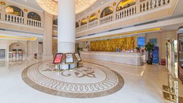 A spacious lobby with a central column, a reception desk, and a decorative floor pattern.