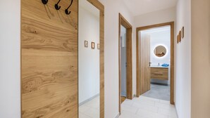 Een gang met houten lambrisering, een spiegel en een badkamer zichtbaar door een open deur.